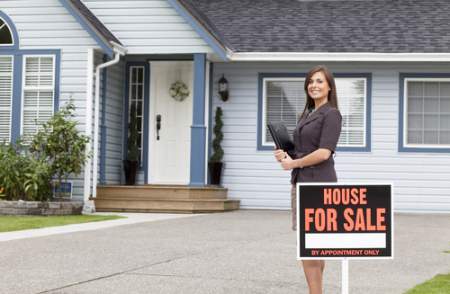 real estate agent beside a home for sale sign