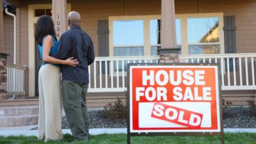 Couple looking at a house with House for Sale Yard Sign